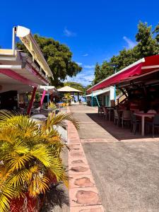 a street with tables and chairs and tables and buildings at le Cottage in Le Moule