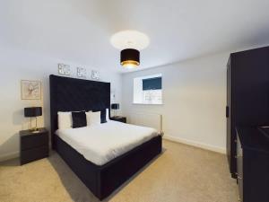 a bedroom with a large bed with a black headboard at Modern 4 Bed Walk to Pubs, Shops and Countryside in Stanhope