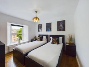 two beds in a bedroom with white walls at Modern 4 Bed Walk to Pubs, Shops and Countryside in Stanhope