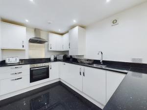 a kitchen with white cabinets and black counter tops at Modern 4 Bed Walk to Pubs, Shops and Countryside in Stanhope +31 photos