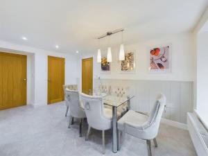 a dining room with a glass table and white chairs at Charming 3 Bedroom Home in the Heart of Stanhope in Stanhope