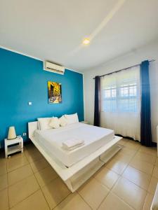 a bedroom with a large white bed with a blue wall at We Call it Home - Bububu Villa in Mtoni +66 photos