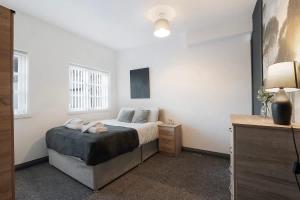 a white bedroom with a bed and a lamp at Spacious 5-Bed Flat in Stockton, Sleeps 9 in Stockton-on-Tees