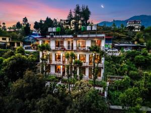 a building on top of a hill with trees at Mukteshwar Valley Resort in Mukteshwar