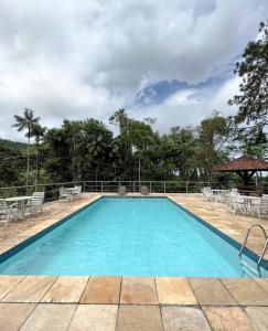 a large swimming pool with chairs and a table at Pousada Aconchego Shangrilla in Penedo