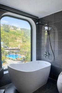 a white bath tub in a bathroom with a window at Mây Trắng Homestay in Tam Ðảo