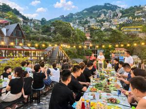 a group of people sitting at long tables eating food at Mây Trắng Homestay in Tam Ðảo