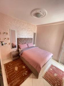 a bedroom with a bed with pink sheets and a mirror at Swiss Home in Agadir