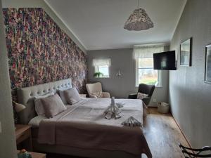 ein Schlafzimmer mit einem großen Bett und einer floralen Wand in der Unterkunft Hotel Fritza in Olofström
