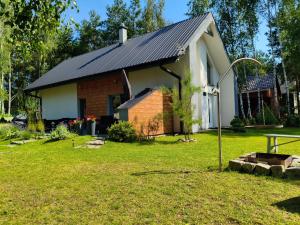 a small house with a black roof on a yard at DOM LETNI Nakielno in Nakielno