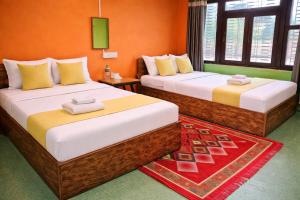 two beds in a room with orange walls at Hotel Butterfly - Peaceful Garden for Nature Lovers in Sauraha +163 photos