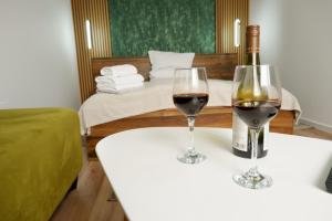 two glasses of wine on a table with a bed at Neva Apartments & Rooms in Făgăraş