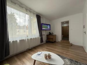 a living room with a table and a large window at Neva Apartments & Rooms in Făgăraş