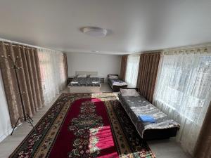 a living room with two beds and a rug at Center guesthouse in Kochkorka
