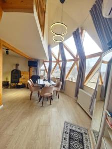 a living room with a table and chairs and windows at Dom Vladeasa in Rogojel