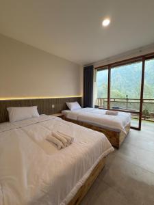 two beds in a room with a large window at HLB Homestay in Ngadisari