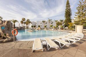 a group of lounge chairs and a swimming pool at BLUESEA Costa Bastian in Costa Teguise +52 photos