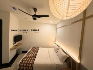 a hotel room with a bed and a ceiling fan at Tokiyo Suites Hotel Kinta River Ipoh Town in Ipoh