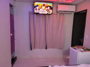 a bathroom with a television on a wall with pink curtains at Hotel Suíte in Brasília