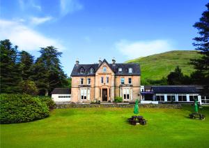 an old house with a green field in front of it at The Caledonian Claymore Hotel in Arrochar