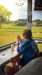 a woman sitting at a table with a drink at Joni Ubud Hostel in Ubud