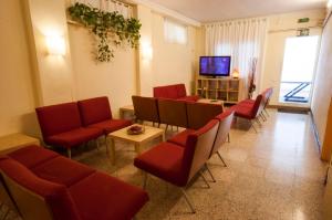 Una sala de espera con sillas rojas y un televisor de pantalla plana. en Studio Hostel, en Barcelona