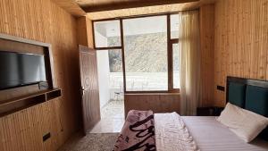 a bedroom with a bed with a television and a window at Harsil River Retreat in Harsil