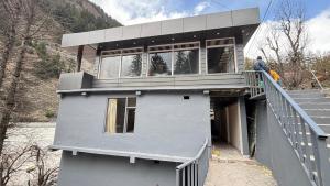a man standing on the balcony of a house at Harsil River Retreat in Harsil