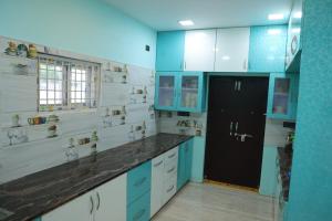 a kitchen with blue and white cabinets and a black door at Premium House or Office In Amaravati in Sūriapālem