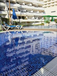 a swimming pool with a blue tile floor and a building at Sanmarcos 2 in Adeje