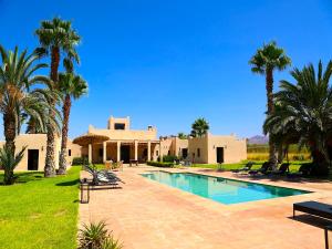 a villa with a swimming pool and palm trees at Palais Nova in Marrakesh