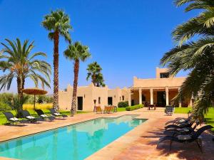 a villa with a swimming pool and palm trees at Palais Nova in Marrakesh