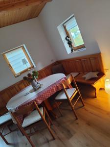 a dining room with a table and chairs and two windows at Romantic cabin in the woods - Fesnga, Slovenia in Slovenj Gradec