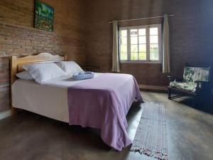 a bedroom with a large bed and a brick wall at Chalé Guaíras in Mulungu