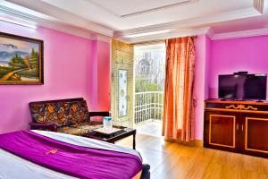 a room with pink walls and a couch and a tv at Hotel Mount View in Kodaikānāl