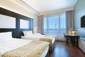 a hotel room with two beds and a desk and a television at Scandic Ruoholahti in Helsinki