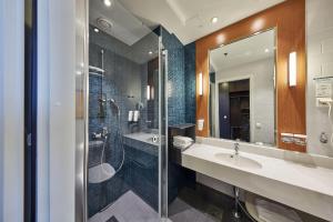 a bathroom with a sink and a shower and a mirror at Scandic Ruoholahti in Helsinki