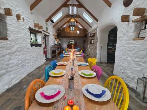 a long wooden table in a restaurant with colorful chairs at Newgale Lodge in Newgale