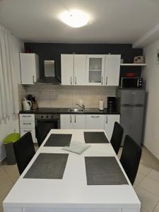 a kitchen with a white table with chairs and a kitchen with white cabinets at Apartments A&A in Bibinje