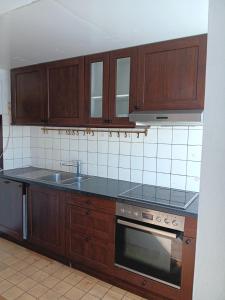 eine Küche mit Holzschränken, Spüle und Herd in der Unterkunft Charmant 90 E in Lichterfelde