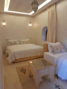a bedroom with two beds and a table in it at Riad NACIRIA in Aït Ourir