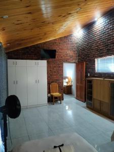 a kitchen with white cabinets and a brick wall at The Bay Inn in Port Elizabeth