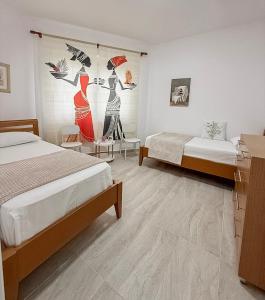 a bedroom with two beds and a mural of women at VERA apartament in Fushë-Draç