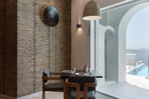 a dining room with a table and chairs next to a window at Hom Santorini in Oia +26 photos