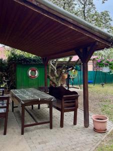 a picnic table and two chairs under a wooden pavilion at Demeter Vendégház in Tiszanána