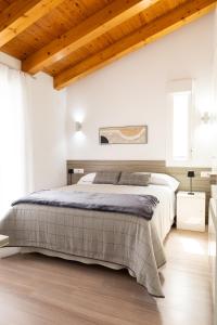 a white bedroom with a large bed and wooden ceilings at Rolix hc Hostal in Fuente-Álamo