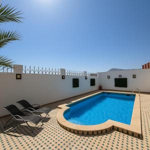 a swimming pool with chairs next to a building at Villa Adan in Sidi Salah