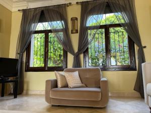 a living room with a couch and two windows at Villa Adan in Sidi Salah