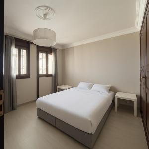a white bedroom with a bed and a pendant light at Villa Adan in Sidi Salah +25 photos