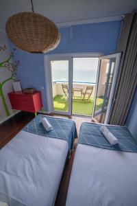 two beds in a room with a view of the ocean at Saltline Surf House Ericeira in Ericeira